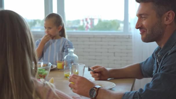 Ευτυχισμένος πατέρας τρώει πρωινό με την οικογένεια στο τραπέζι στην κουζίνα - Πλάνα, βίντεο