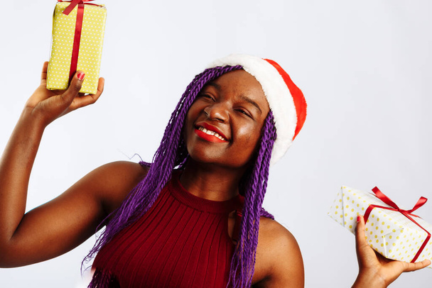 Happy African Santa Woman hymyilee ja pitää lahjapakkausta jouluksi tai uudeksi vuodeksi. Eristetty valkoisella pohjalla. - Valokuva, kuva