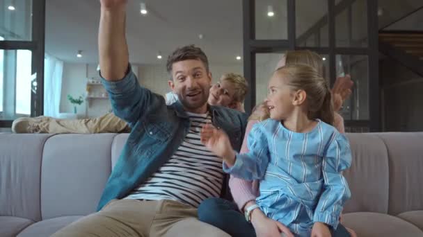 Familia feliz con las manos agitadas mirando a la cámara durante el chat de vídeo en casa - Metraje, vídeo