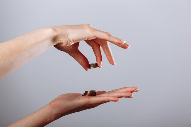 Női kéz ad vagy vesz arany érme egy másik kéz elszigetelt fehér háttér, krízis koncepció. - Fotó, kép