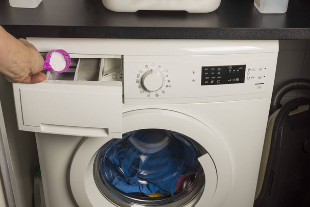 Close-up vista da mão masculina colocar detergente na máquina de lavar roupa
. - Foto, Imagem