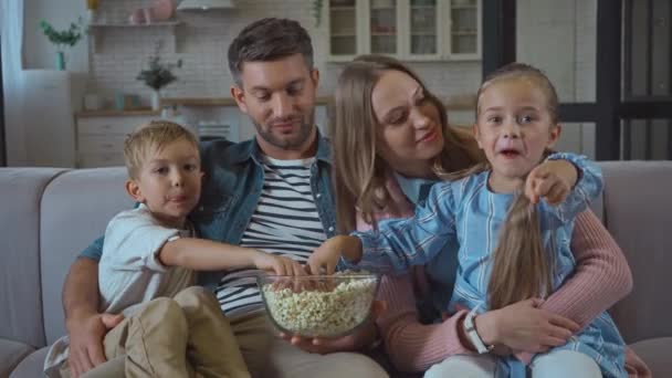 Famiglia con popcorn parlando mentre guarda la fotocamera a casa - Filmati, video