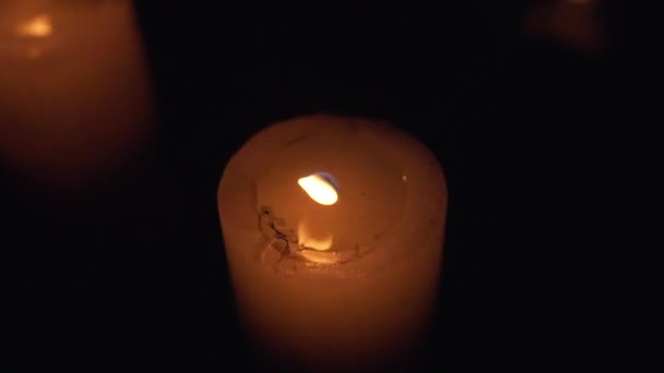 La fiamma arancione dell'alta candela ondeggia fortemente dal vento, quasi si spegne ma continua a bruciare al buio - Filmati, video