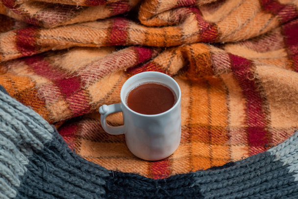 old checkered blanket with orange red and brown patterns. autumn background. cozy woolly gray scarf. cup of coffee - Fotoğraf, Görsel