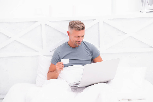 Payment and purchase. Online shopping. Work from home. Checking messages. Mature guy pajamas in bed. Businessman with computer. Hipster work on laptop. Bedroom rest. Remote job. Online communication - Φωτογραφία, εικόνα
