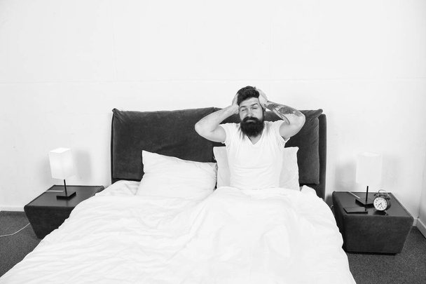 Hangover effect. Hipster got terrible headache in morning. Bearded man suffer from headache in bed. Headache attack. Migraine or tension headache. Cold and flu symptoms. Kill pain. Treat disease - 写真・画像
