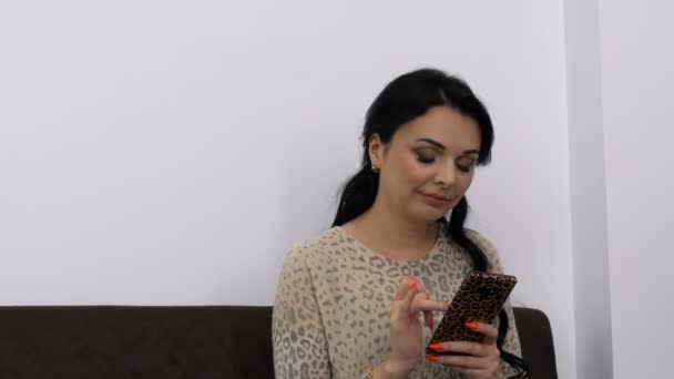 Красива молода жінка з вечірнім макіяжем друкує щось на телефоні в кімнаті
 - Кадри, відео