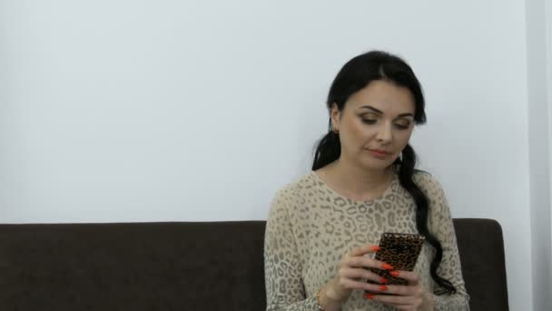 mooie jonge vrouw met avond make-up afdrukken iets op de telefoon in de kamer - Video