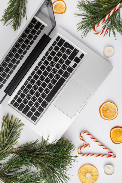 Christmas, winter, new year composition. Home office desk workspace with Fir tree branches, dried oranges, candies, candles on white background. Flat lay, top view - Фото, зображення