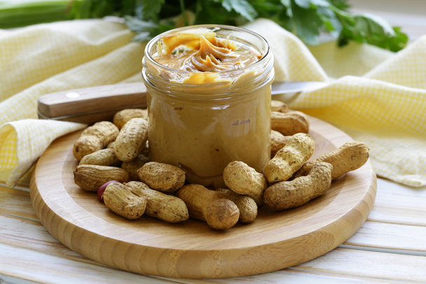 Домашнє арахісове масло з цілими горіхами на дерев'яному столі
 - Фото, зображення