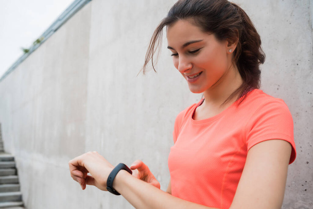 Kobieta fitness sprawdza czas na inteligentnym zegarku. - Zdjęcie, obraz