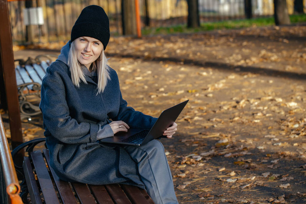 Красива біла дівчина 30 років сидить у громадському парку і дивиться на ноутбук
 - Фото, зображення