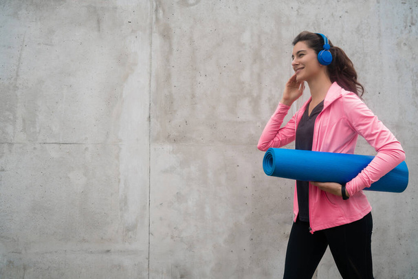 Athletic woman holding a training mat. - Foto, Bild