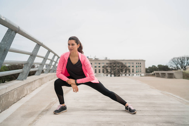 Athletic woman stretching legs before exercise. - Φωτογραφία, εικόνα