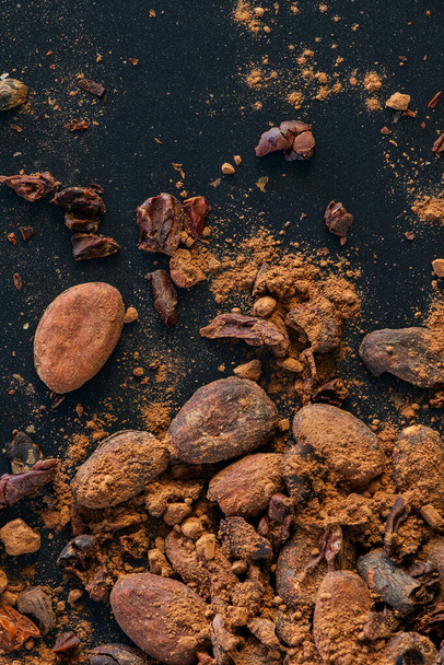 Семена бобов какао, перья какао и порошок какао изолированы на черном фоне. - Фото, изображение