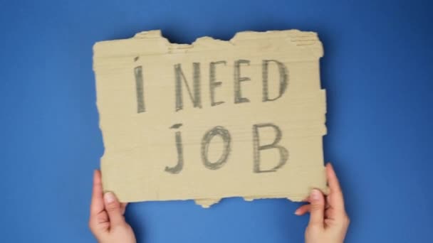 kus papíru s nápisem Potřebuji práci, koncept nezaměstnanosti na pozadí globálního modrého pozadí  - Záběry, video