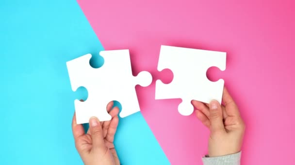 empty paper white pieces of puzzles in female hands, puzzle connected, colorful background, top view - Footage, Video