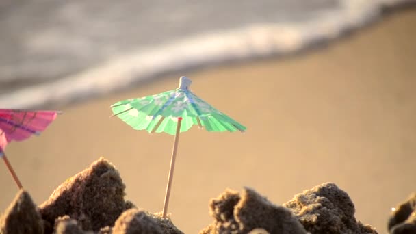 Pequeñas sombrillas de papel para un puesto de cócteles en la playa de arena - Metraje, vídeo