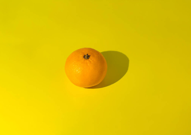 Mandarin on yellow background centered. Photo taken with selective focus and noise effect - Photo, image