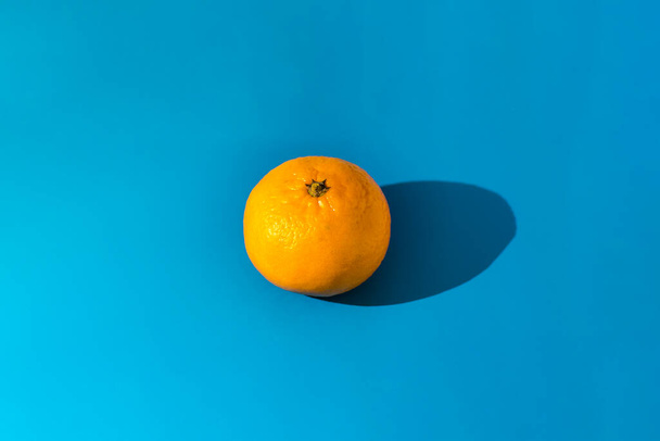 Mandarin on blue background centered. Photo taken with selective focus and noise effect - 写真・画像