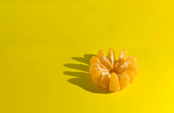Peeled tangerine on a yellow background. Photo taken with selective focus and noise effect - Фото, изображение