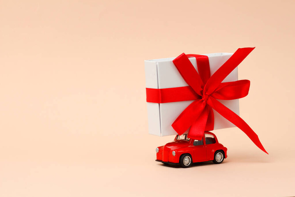 Valentine's Day,New year, small red retro toy car with a big gift on the roof on a pink background. Delivery of gifts for Christmas, World Women's Day. Sale concept.Copy space - Foto, imagen