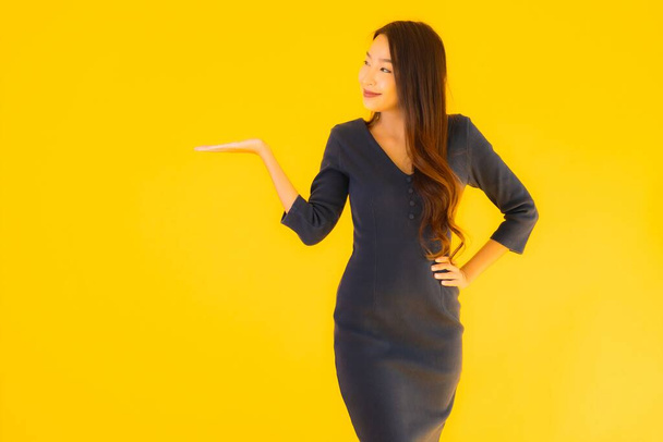 Portrait beautiful young asian woman with action on isolated yellow background - Photo, image