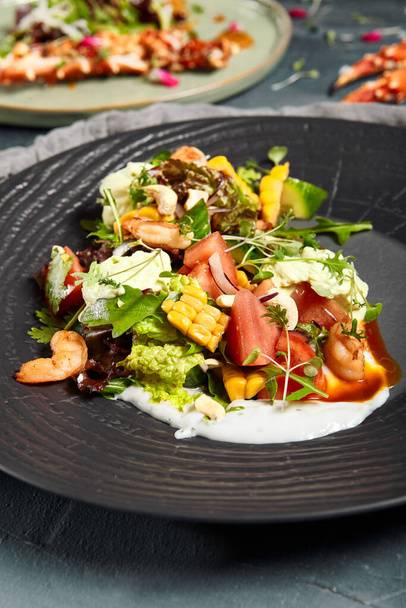 Delicious salads served on plates side view. Restaurant dishes, trendy salads with shellfish and vegetables with old silverware on grey texture background - 写真・画像