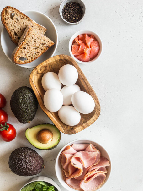 Verschiedene Rohstoffe für die Zubereitung von Frühstück. Frische Eier, Schinken, Lachs, Gemüse. Ansicht von oben. Kopierraum - Foto, Bild