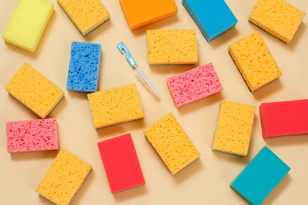 Sponges of different colors and a small brush on the beige background. Top view. Washing and cleaning set. - Foto, Bild