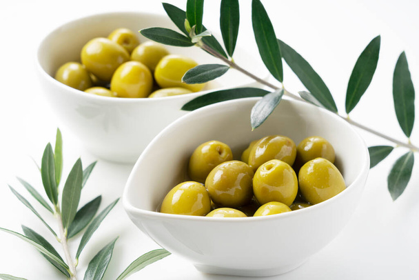 Valkoiselle pohjalle sijoitetut suolatut oliivit ja oliivipuun oksat - Valokuva, kuva