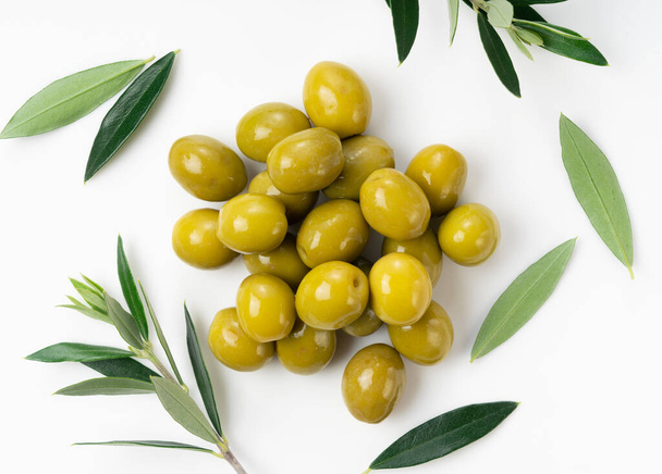 Un primer plano de las ramas de olivo con aceitunas saladas colocadas sobre un fondo blanco. Una vista desde arriba - Foto, imagen