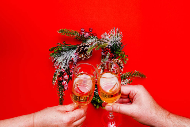 トップ表示2人の男性と女性の手は、シャンパンのグラスを保持しています,赤の背景にフラットレイリース - 写真・画像