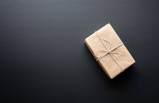 Caja de regalo marrón en estilo bricolaje sobre fondo oscuro.giving y cocepts aniversario vista idea.top - Foto, imagen