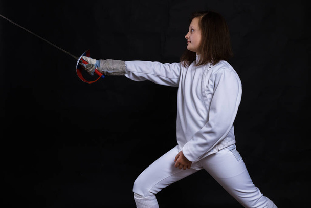Teenage girl fencer dressed in uniform with epee and helmet - Foto, Bild