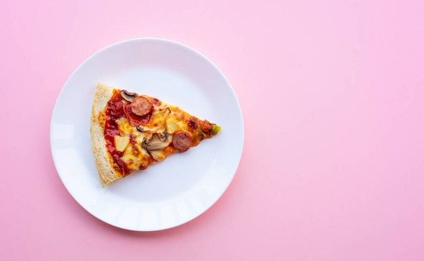 Bovenaanzicht van een stuk pizza op witte schotel.Simple food en eetconcepten - Foto, afbeelding