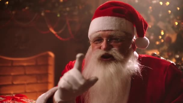 aktor odgrywa rolę Świętego Mikołaja, trzymając palec w pobliżu ust dla ciszy na Boże Narodzenie urządzone pokoju, cichy znak w gestykulacji - Materiał filmowy, wideo