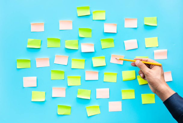 Üzletember színes jegyzettömbbel kék háttérrel.ötletek kreativitás fogalmak - Fotó, kép