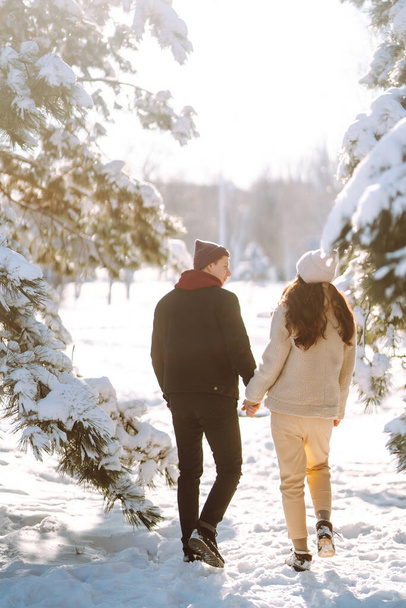 Happy Couple in love walking and having fun in snow forest. Young man and woman playing in the snow on winter holidays. Christmas, New year. Winter lifestyle. - Zdjęcie, obraz