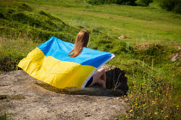 A girl in a park holding a flag on the back Ukraine - Фото, изображение
