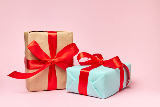 Рождественские или новогодние подарочные коробки с красными лентами на розовом фоне. Крупный план, избирательный фокус - Фото, изображение