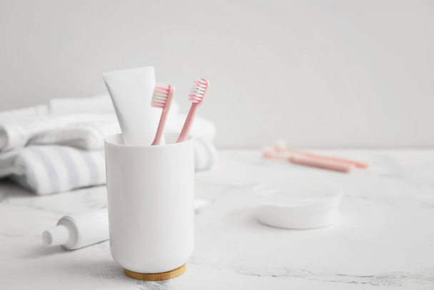 Holder with toothbrushes and paste on table in bathroom - Φωτογραφία, εικόνα