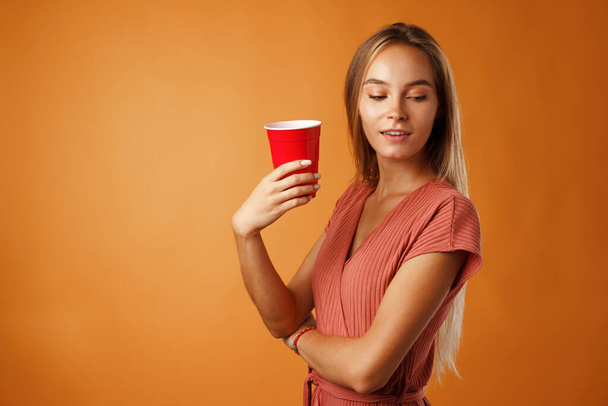 Attractive young woman standing and drinking hot drink - Foto, afbeelding