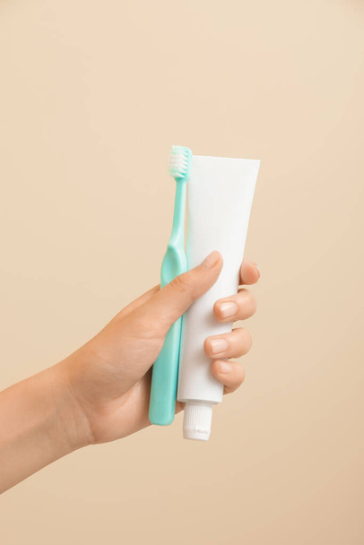 Female hand with toothbrush and paste on color background - Photo, image
