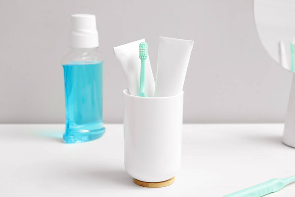 Cepillo de dientes con enjuague bucal y pasta en la mesa en el baño - Foto, Imagen