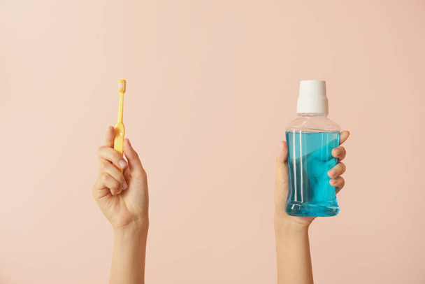 Female hands with tooth brushes and mouth rinse on color background - Photo, Image