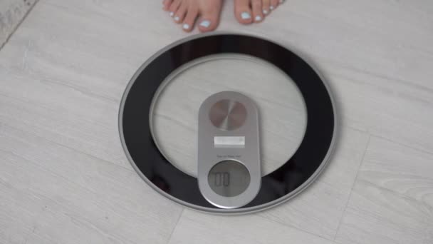 Een vrouw staat op elektrische weegschaal, haar gewicht is 76,6 kilogram - Video