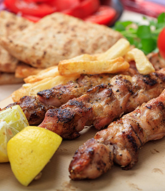 Souvlaki greek food. Grilled meat skewers served with fried potatoes, pita bread and lemon, closeup view. Turkish shish kebab, shashlik - Photo, Image