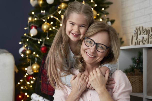 Portrait of happy grandmother and granddaughter embracing in Christmas time                                - Фото, изображение