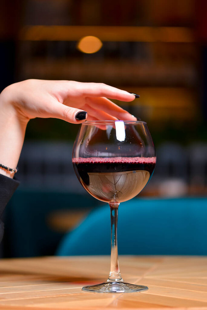 Red wine glass. Elegant womans hand and a glass of wine on the table in restaurant. Still life, eating out concept. Close up. - Fotoğraf, Görsel